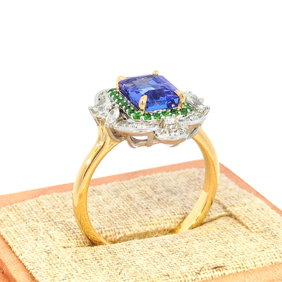 18ct Yellow & White Gold Ring set with Tanzanite. Tsavorite & Diamonds This beautiful ring is set with a quality Tanzanite of nearly 2 carats in the centre, surrounded by vibrant green Tsavorites and finished with round and marquise diamonds in white gold. A true statement piece! Tanzanite = 1.91cts Tzavorite = 0.26cts TDW Diamonds = 0.35cts H/Si RBCs